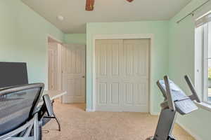 Carpeted office featuring ceiling fan