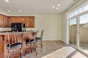 Kitchen featuring black fridge with ice dispenser and a breakfast bar. Natural Light pours in from the sliding doors. The kitchen and patio connect for a welcoming entertaining space.