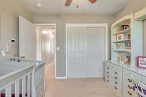 Bedroom with light carpet, a closet, ceiling fan.