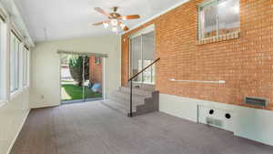 Unfurnished room featuring carpet floors, ceiling fan, lofted ceiling, stairs, and a textured ceiling