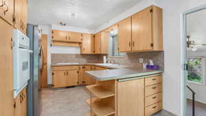 Kitchen with tasteful backsplash, a sink, a peninsula, open shelves, and white appliances