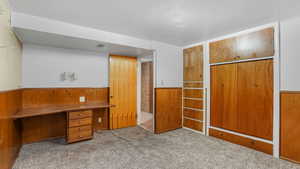 Unfurnished office with wooden walls, a wainscoted wall, and carpet floors
