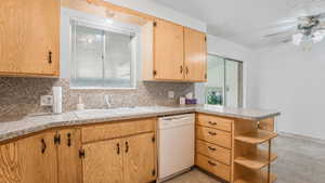 Kitchen featuring white dishwasher, a sink, backsplash, light countertops, and a peninsula