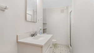 Full bathroom featuring vanity, a stall shower, toilet, tile patterned floors, and baseboards