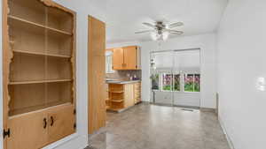 Unfurnished dining area featuring ceiling fan, baseboards, and a textured ceiling