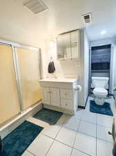 Bathroom with toilet, a textured ceiling, vanity, and tile patterned flooring