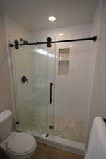 Custom shower with subway tile, stone, and frameless shower door