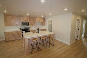 Kitchen featuring stainless steel appliances, light brown cabinetry, and light hardwood / wood-style flooring