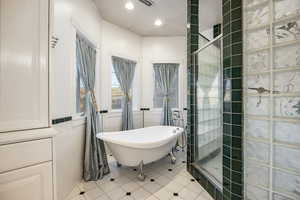 Bathroom with tile patterned floors, tiled shower, recessed lighting, tile walls, and a soaking tub