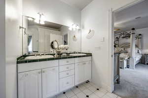 Full bath with double vanity, baseboards, tile patterned flooring, and a sink