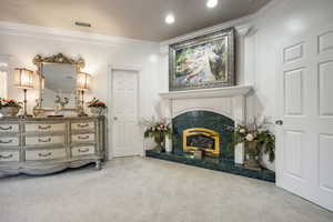 Living area featuring crown molding, carpet flooring, visible vents, and a tile fireplace