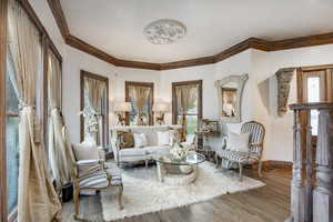 Living area featuring crown molding, baseboards, a textured wall, and wood finished floors