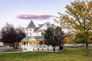 Victorian home featuring a shingled roof, fence, covered porch, and a front yard