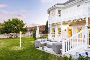 Yard at dusk featuring fence, an outdoor hangout area, a mountain view, a patio area, and a balcony