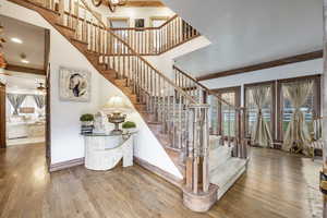 Stairway featuring crown molding, baseboards, wood finished floors, and a high ceiling