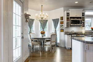 Dining room featuring baseboards, visible vents, dark wood-style flooring, and a notable chandelier