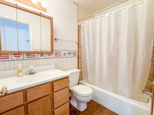 Full bathroom with vanity, tile patterned floors, toilet, and shower / bath combination with curtain