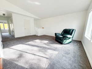 Living area featuring a wealth of natural light, lofted ceiling, and carpet