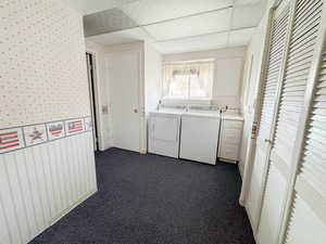 Washroom with cabinets, washing machine and dryer, and dark carpet