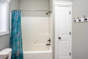 Primary ensuite bathroom featuring shower / bathtub combination with curtain and toilet