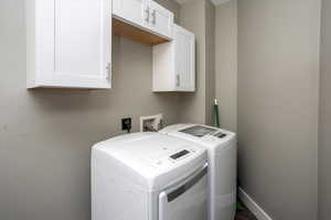 Washroom off kitchen with washer and dryer and cabinets