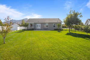 Rear view of property with a yard, a patio area, and a mountain view