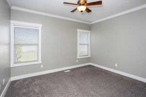 Primary bedroom. Carpeted room featuring ornamental molding and ceiling fan