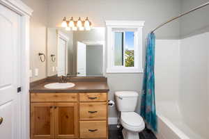 Primary, ensuite bathroom with tile patterned flooring, shower / bath combo, vanity, and toilet