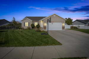 Single story home with a garage and a lawn