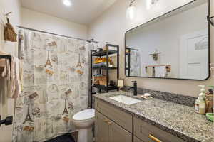 Bathroom with a shower with shower curtain, vanity, and toilet