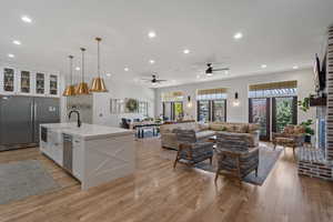 Kitchen with pendant lighting, a wealth of natural light, a kitchen island with sink, and white cabinets