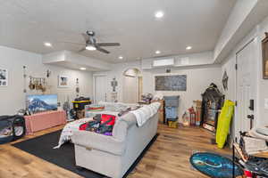 ADU: Living room featuring hardwood / wood-style flooring, ceiling fan, a wall mounted air conditioner, and a textured ceiling