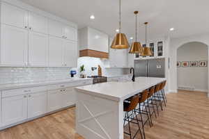 Kitchen featuring white cabinets, sink, a kitchen island with sink, light hardwood / wood-style flooring, and appliances with stainless steel finishes