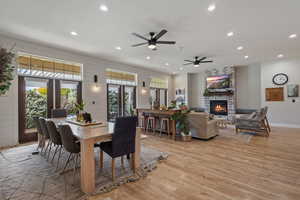 Dining room featuring ceiling fan, a fireplace, french doors, and light hardwood / wood-style floors