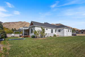 Back of property featuring a deck with mountain view and a lawn