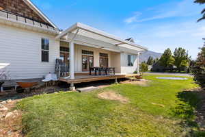 Back of house with a deck with mountain view and a lawn