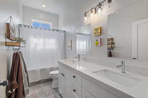 Full bathroom with shower / bath combination with curtain, vanity, and toilet