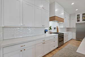 Kitchen with premium appliances, light hardwood / wood-style flooring, and white cabinetry