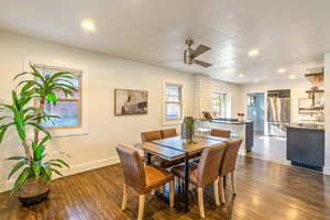 Main level dining space and kitchen featuring ceiling fan and dark hardwood flooring