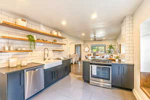 Kitchen and dining area with ceiling fan, tasteful backsplash, sink, tile flooring, and appliances with stainless steel finishes