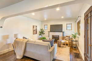 Main level living room with a fireplace and dark hardwood floors - lots of natural light