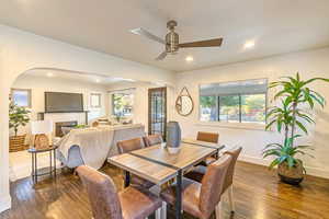 Main level dining/living space featuring a fireplace, ceiling fan, and dark hardwood flooring