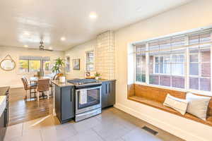 Kitchen and dining room featuring kitchen peninsula, ceiling fan, stainless steel gas range oven, and hardwood flooring