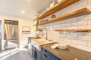 Kitchen featuring sink, decorative light fixtures, backsplash, appliances with stainless steel finishes, and tile floors