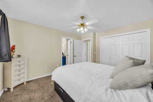 Carpeted bedroom featuring ceiling fan and a closet