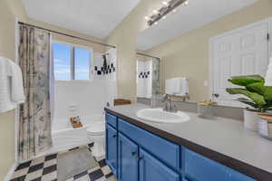 Full bathroom with vanity, toilet, and shower / bathtub combination with curtain