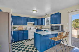 Kitchen with stainless steel appliances, kitchen peninsula, blue cabinetry, and a breakfast bar