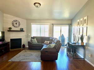 Living room with dark wood-type flooring, vaulted ceiling, and a fireplace