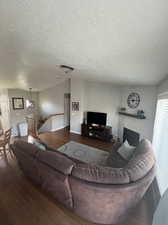 Living room featuring a large fireplace, dark hardwood / wood-style floors, vaulted ceiling, and a textured ceiling