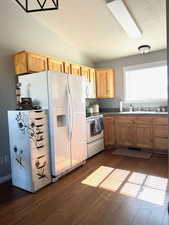 Kitchen featuring white appliances, sink, a textured ceiling, lofted ceiling, and dark wood-type flooring